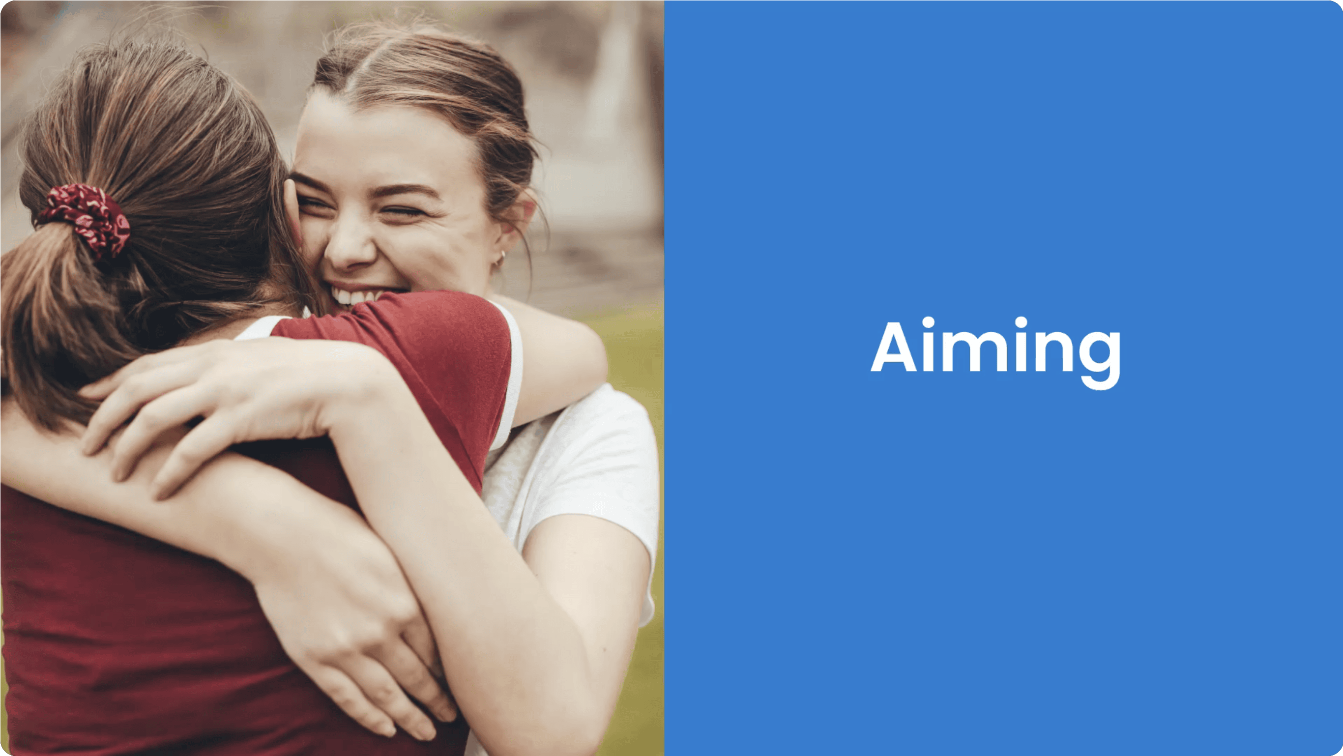 Two women embracing happily in a park, one laughing.